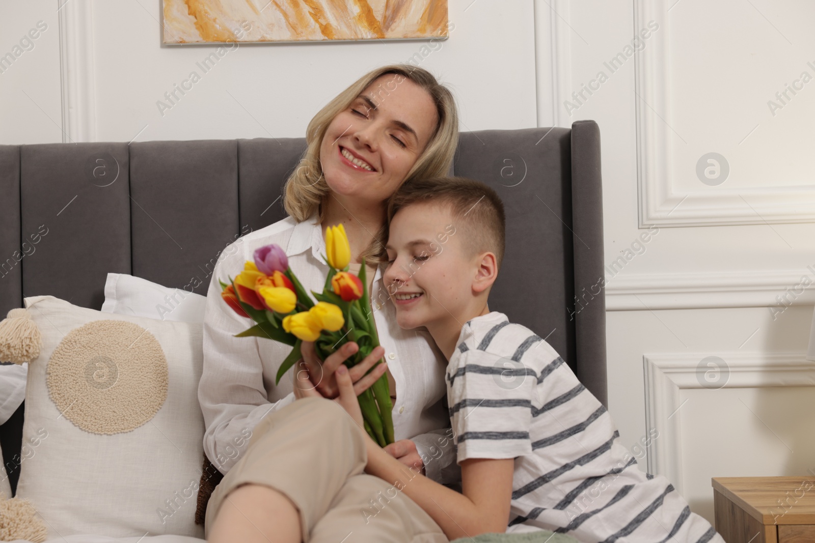 Photo of Happy Mother's Day. Son greeting his mom with flowers at home