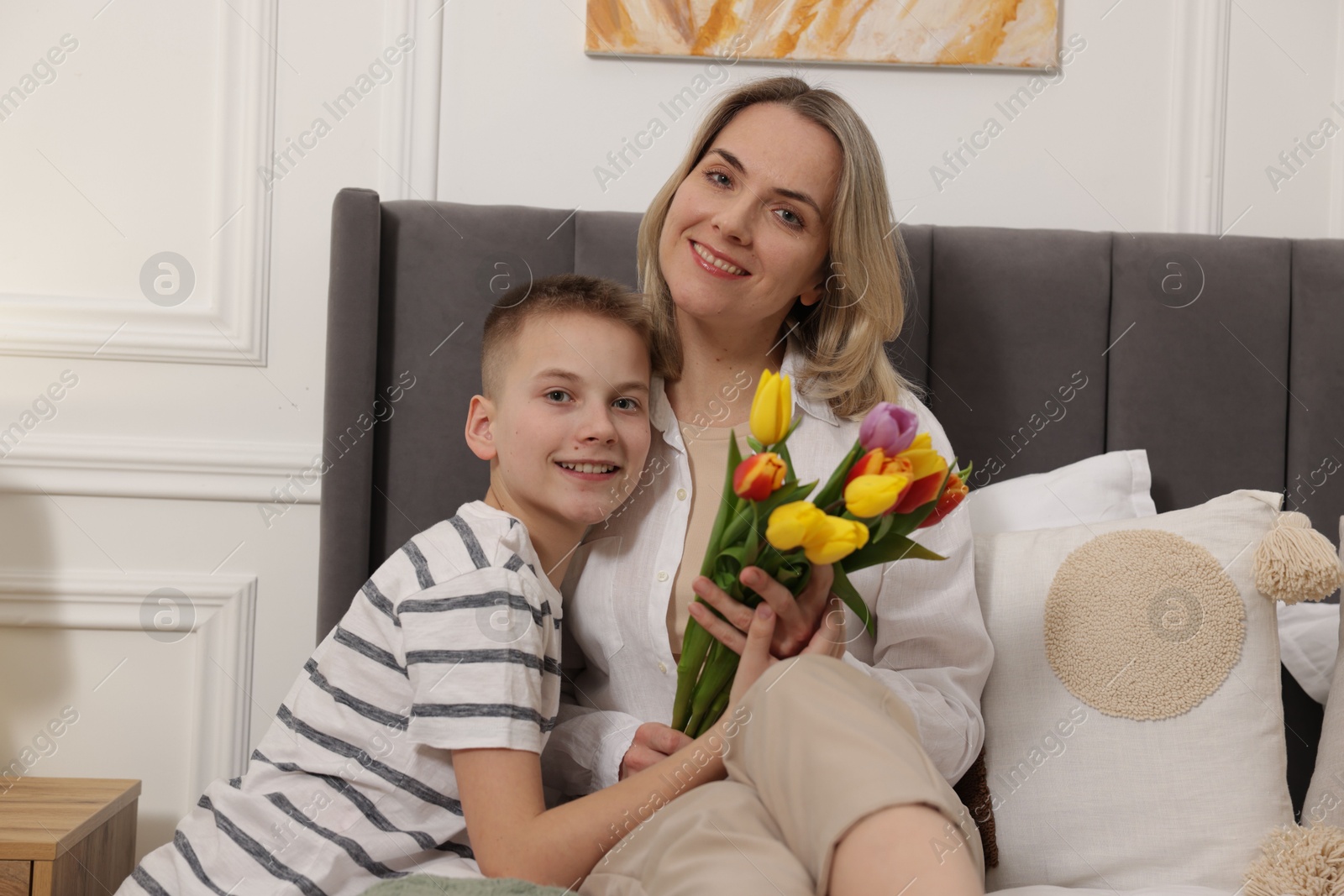 Photo of Happy Mother's Day. Son greeting his mom with flowers at home