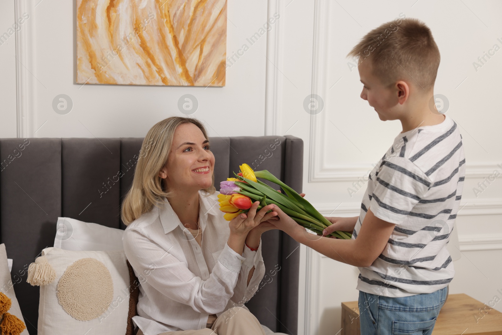 Photo of Happy Mother's Day. Son greeting his mom with flowers at home