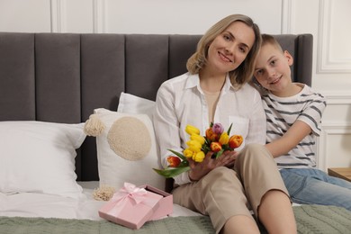 Photo of Happy Mother's Day. Son greeting his mom with flowers and gift at home. Space for text