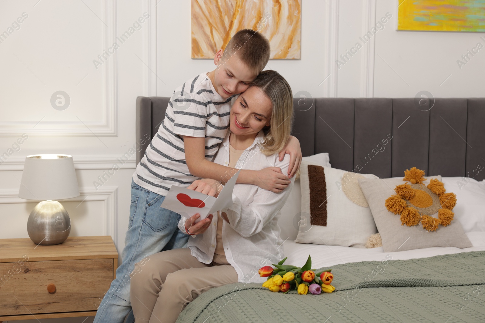 Photo of Happy Mother's Day. Son greeting his mom with flowers and card at home