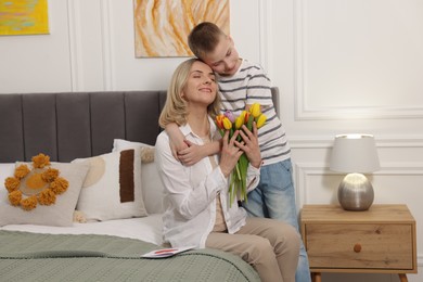 Photo of Happy Mother's Day. Son greeting his mom with flowers at home