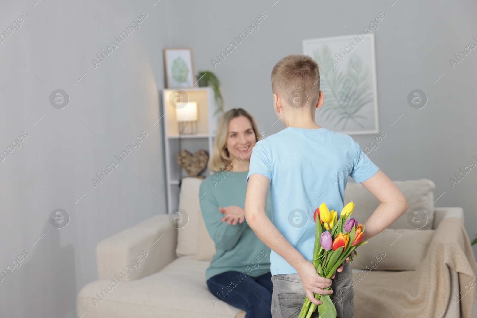 Photo of Happy Mother's Day. Son surprising his mom with flowers at home, selective focus. Space for text