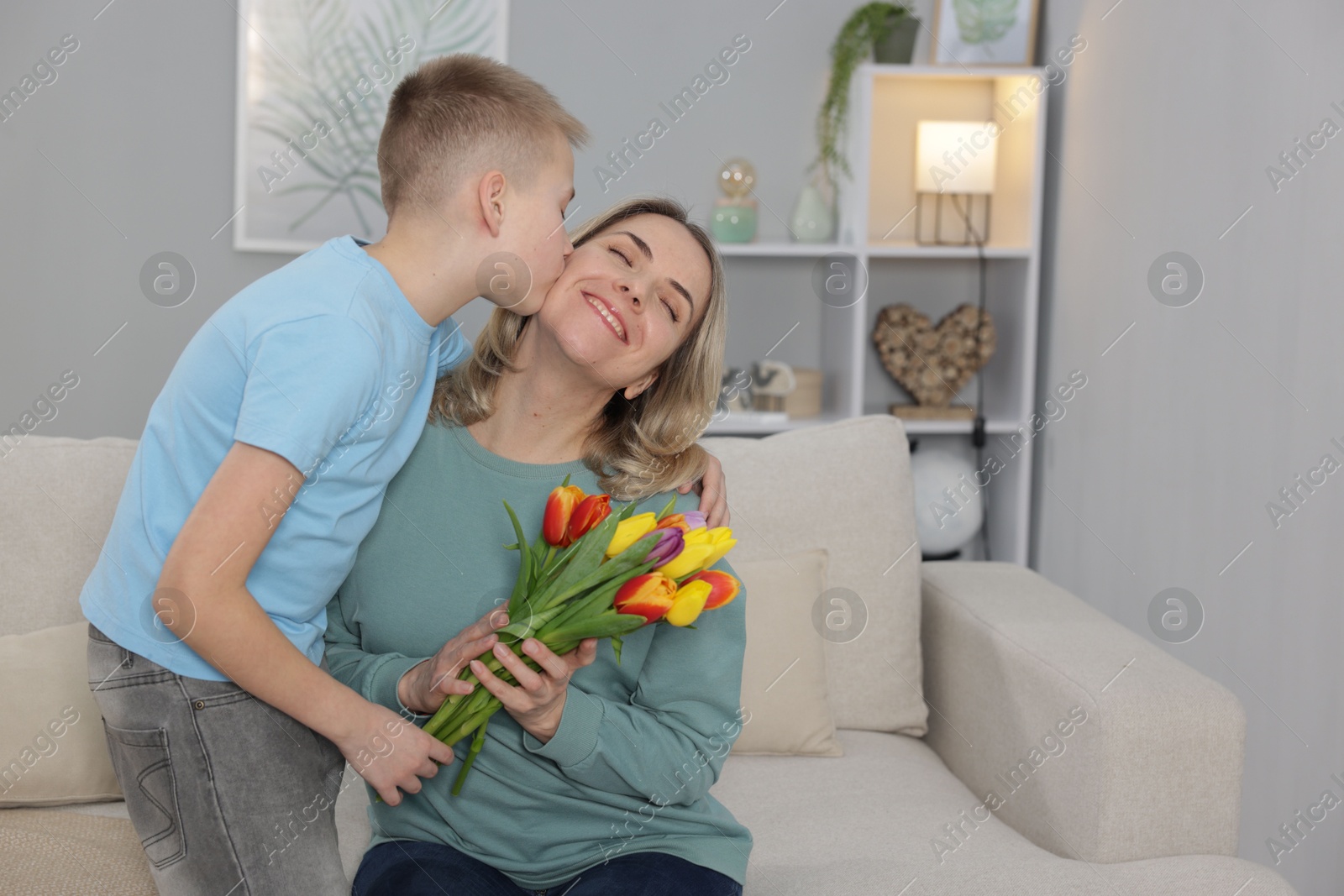 Photo of Happy Mother's Day. Son greeting his mom with flowers at home. Space for text