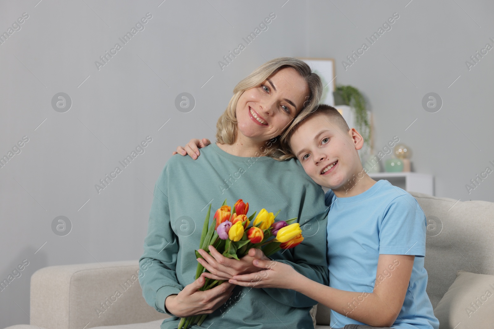 Photo of Happy Mother's Day. Son greeting his mom with flowers at home. Space for text