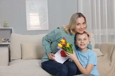 Photo of Happy Mother's Day. Son greeting his mom with flowers and card at home. Space for text