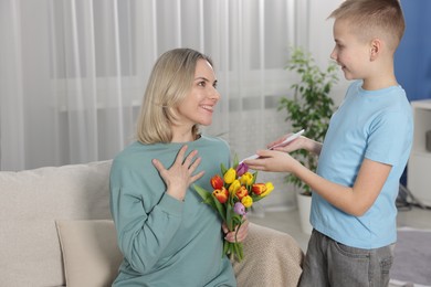 Photo of Happy Mother's Day. Son greeting his mom with flowers and card at home