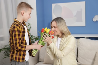 Photo of Happy Mother's Day. Son greeting his mom with flowers at home