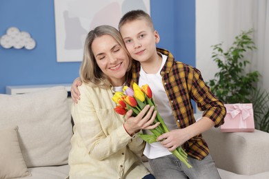 Photo of Happy Mother's Day. Son greeting his mom with flowers at home