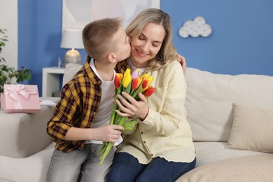 Photo of Happy Mother's Day. Son greeting his mom with flowers at home