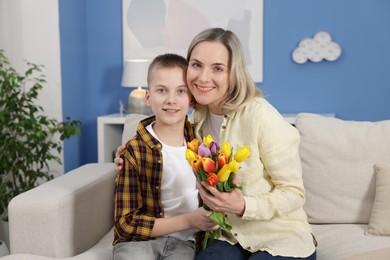 Photo of Happy Mother's Day. Son greeting his mom with flowers at home