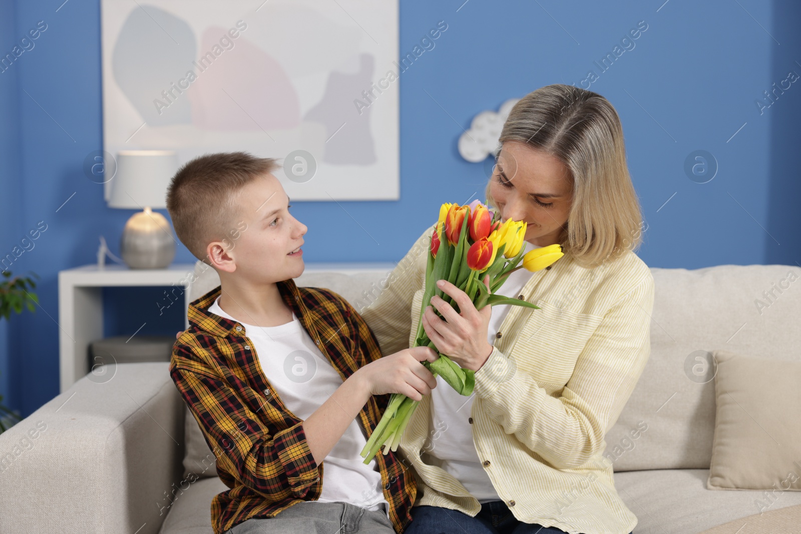 Photo of Happy Mother's Day. Son greeting his mom with flowers at home