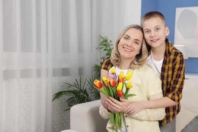 Photo of Happy Mother's Day. Son greeting his mom with flowers at home. Space for text