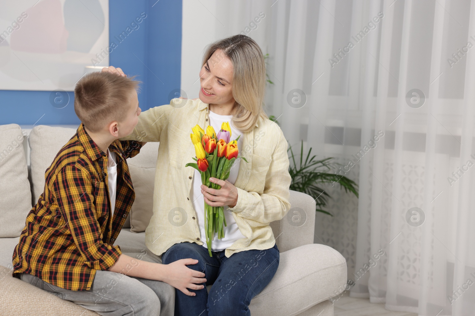 Photo of Happy Mother's Day. Son greeting his mom with flowers at home. Space for text