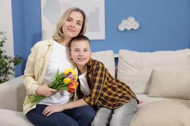 Photo of Happy Mother's Day. Son greeting his mom with flowers at home. Space for text