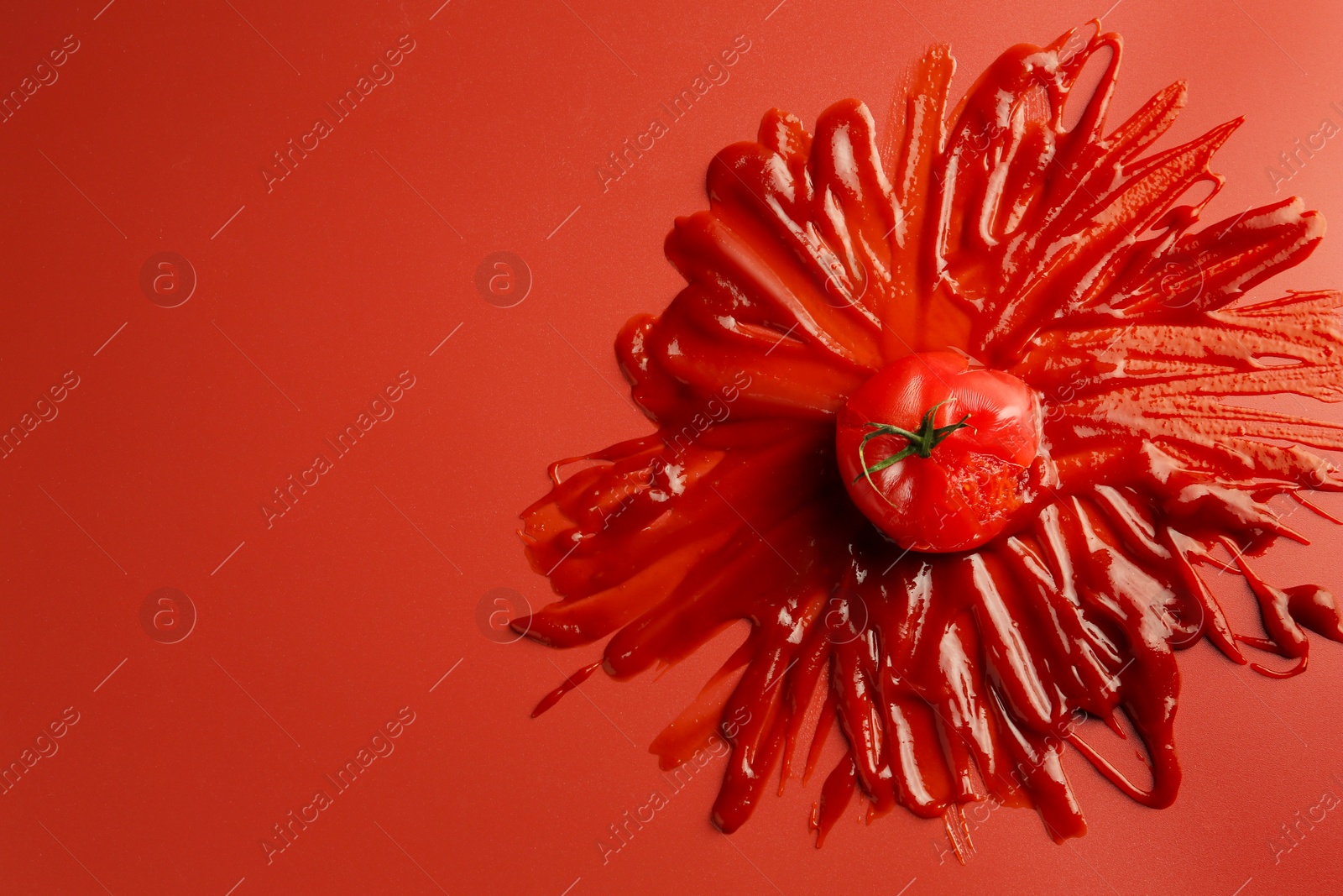 Photo of Tasty ketchup and tomato on red background, top view. Space for text