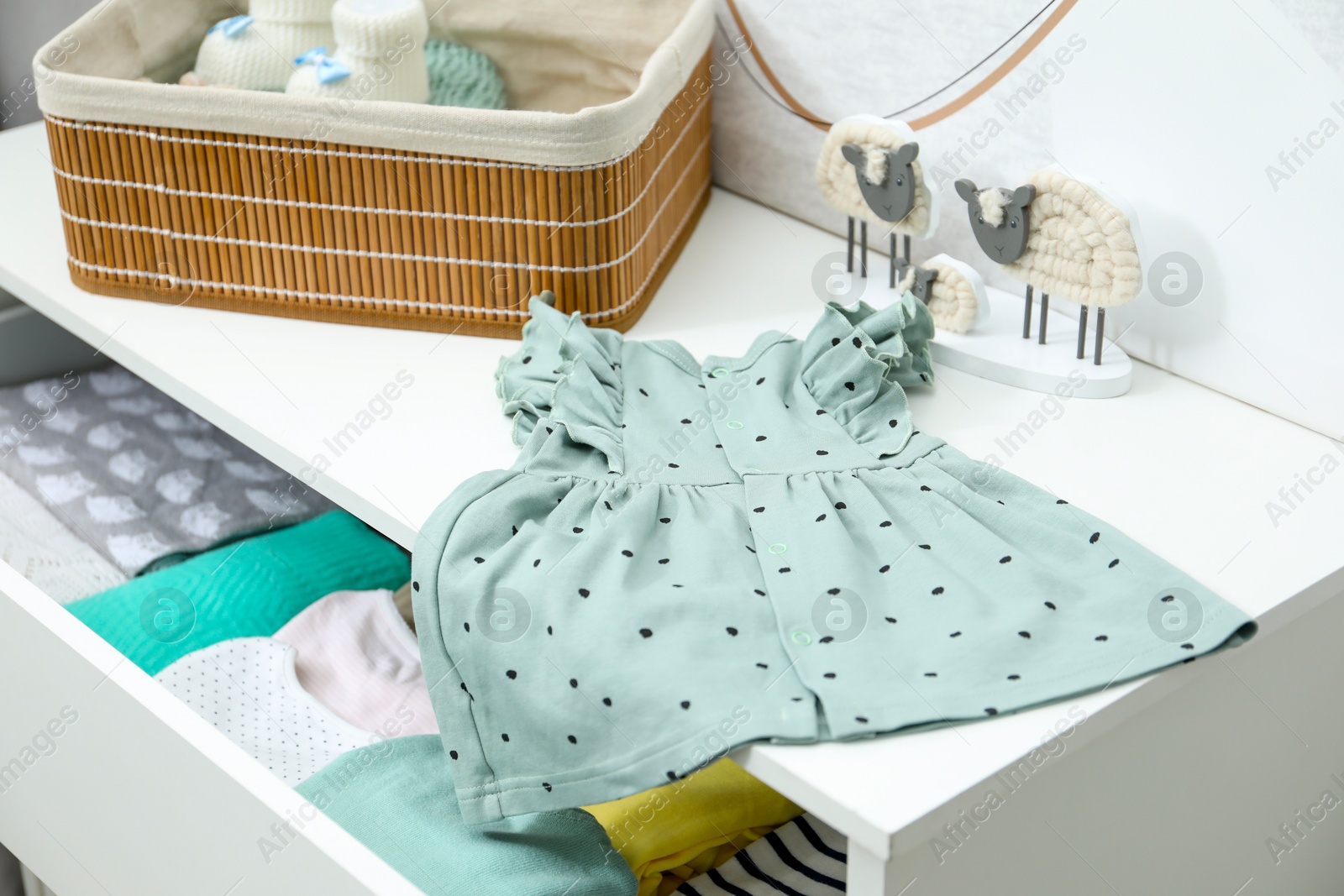 Photo of Baby clothes on white chest of drawers, closeup