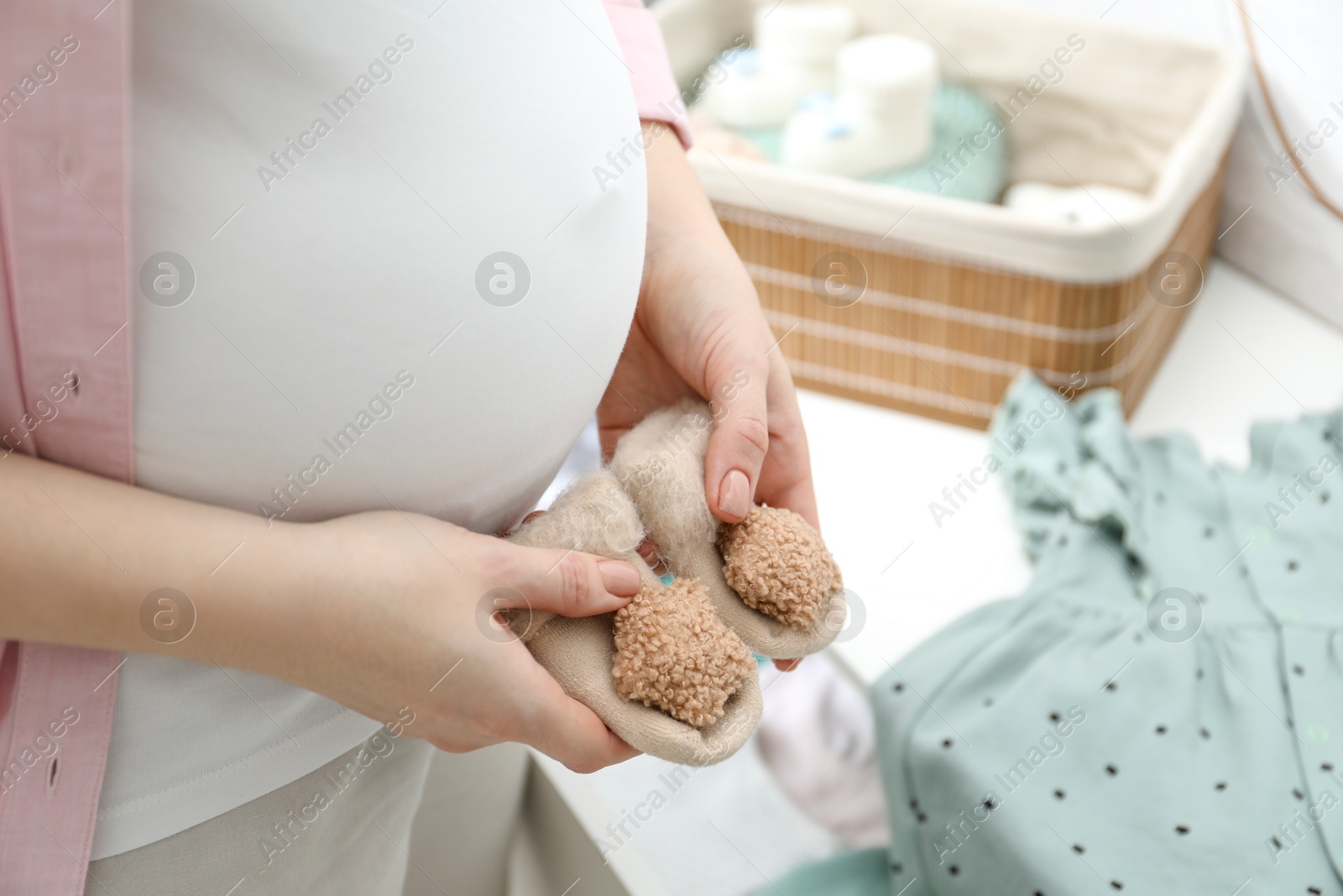 Photo of Pregnant woman with baby socks at home, closeup