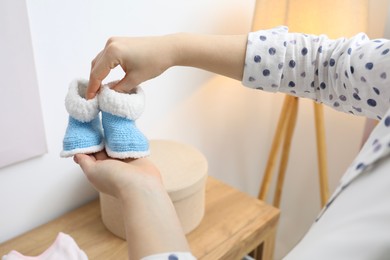 Photo of Woman with baby booties at home, closeup