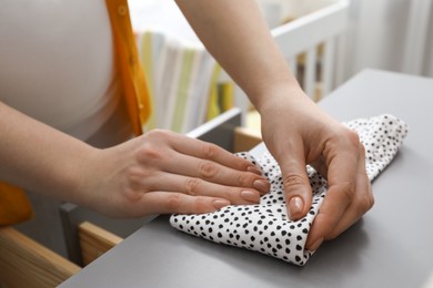 Photo of Woman folding baby clothes at home, closeup