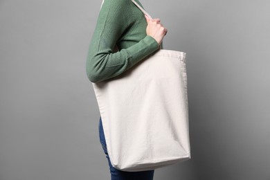 Photo of Woman with blank shopper bag on grey background, closeup. Mockup for design