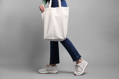 Photo of Woman with blank shopper bag on grey background, closeup. Mockup for design