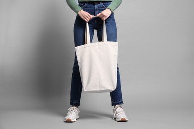 Photo of Woman with blank shopper bag on grey background, closeup. Mockup for design