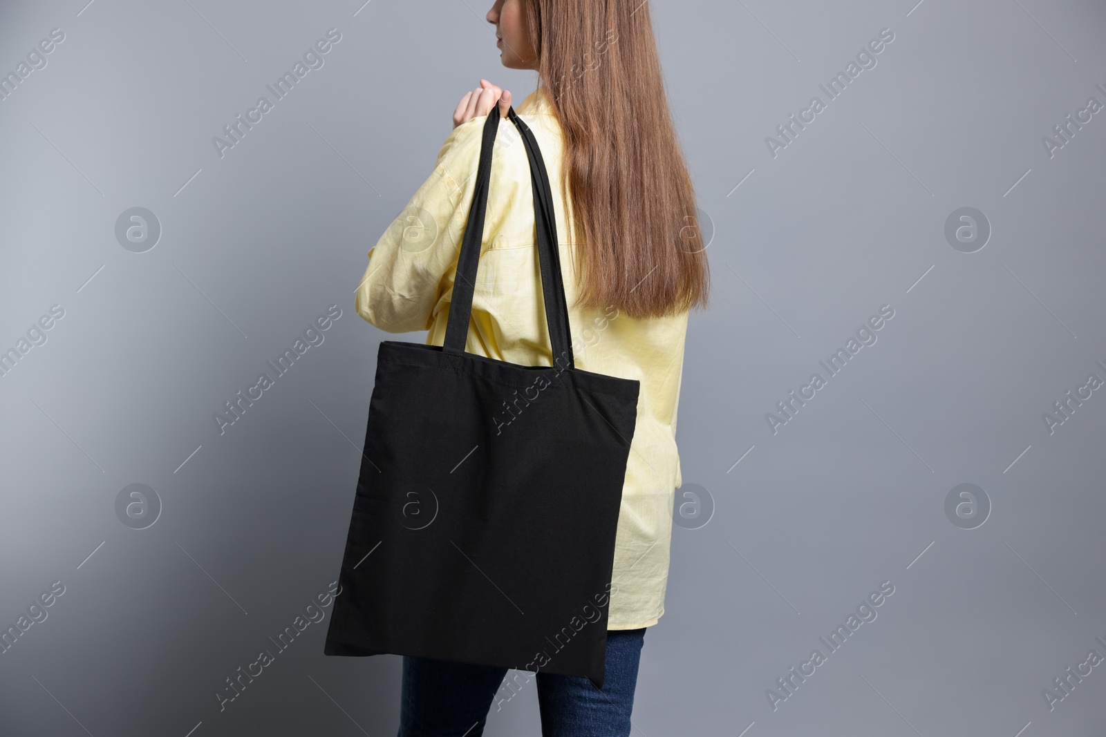 Photo of Woman with blank shopper bag on grey background, closeup. Mockup for design