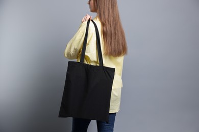 Photo of Woman with blank shopper bag on grey background, closeup. Mockup for design