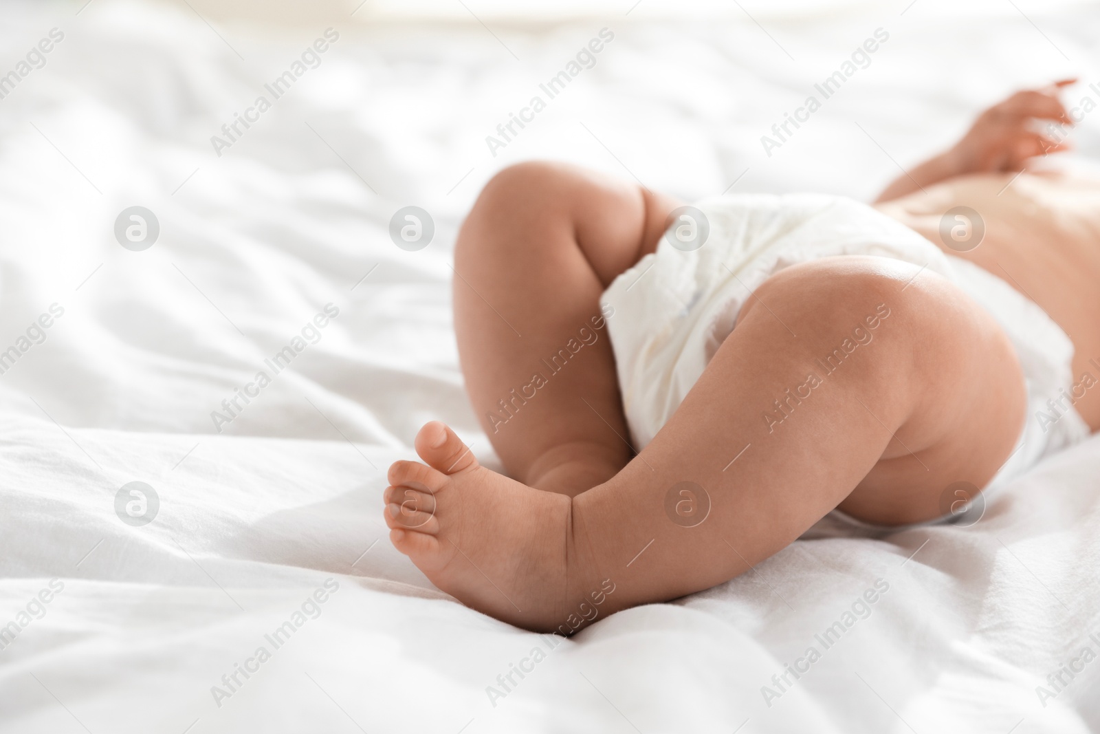 Photo of Cute little baby in diaper on bed, closeup