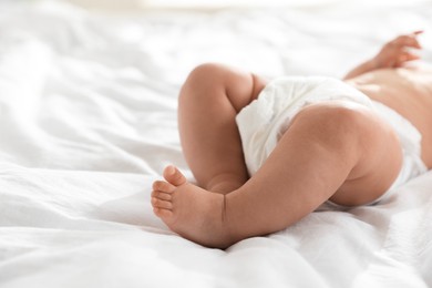 Photo of Cute little baby in diaper on bed, closeup