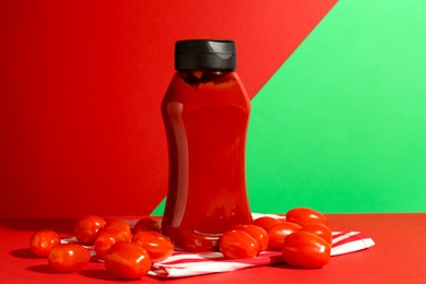 Photo of Bottle of ketchup and tomatoes on color background