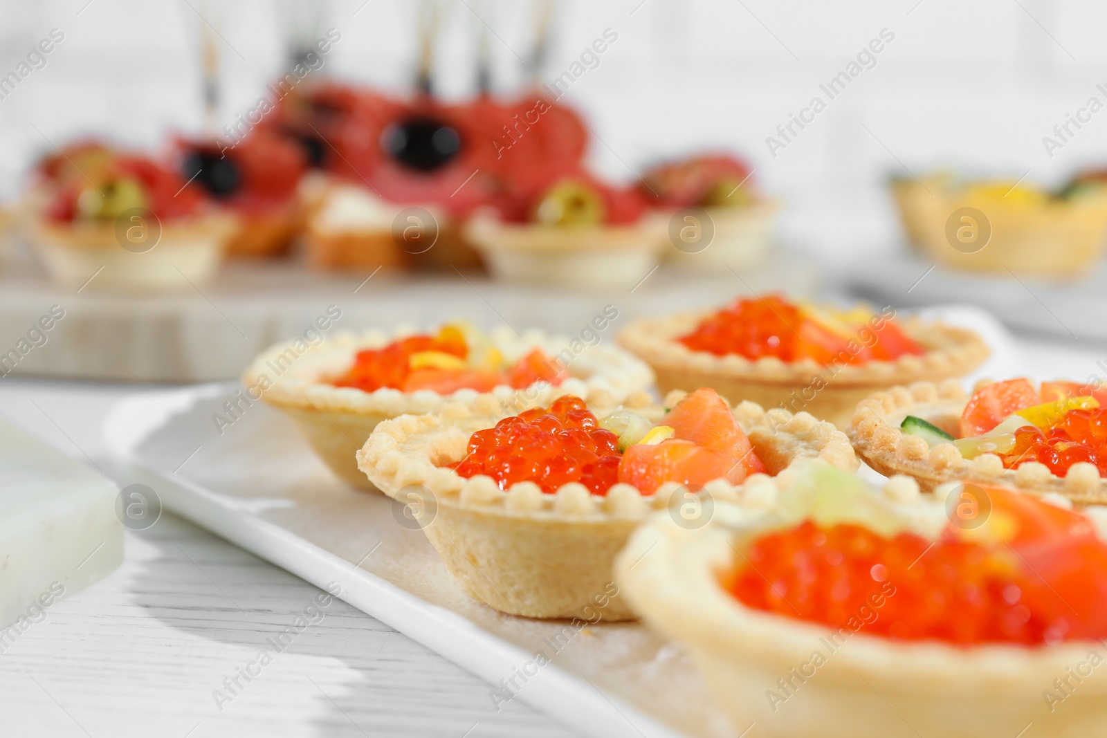 Photo of Many different tasty canapes on white wooden table, closeup