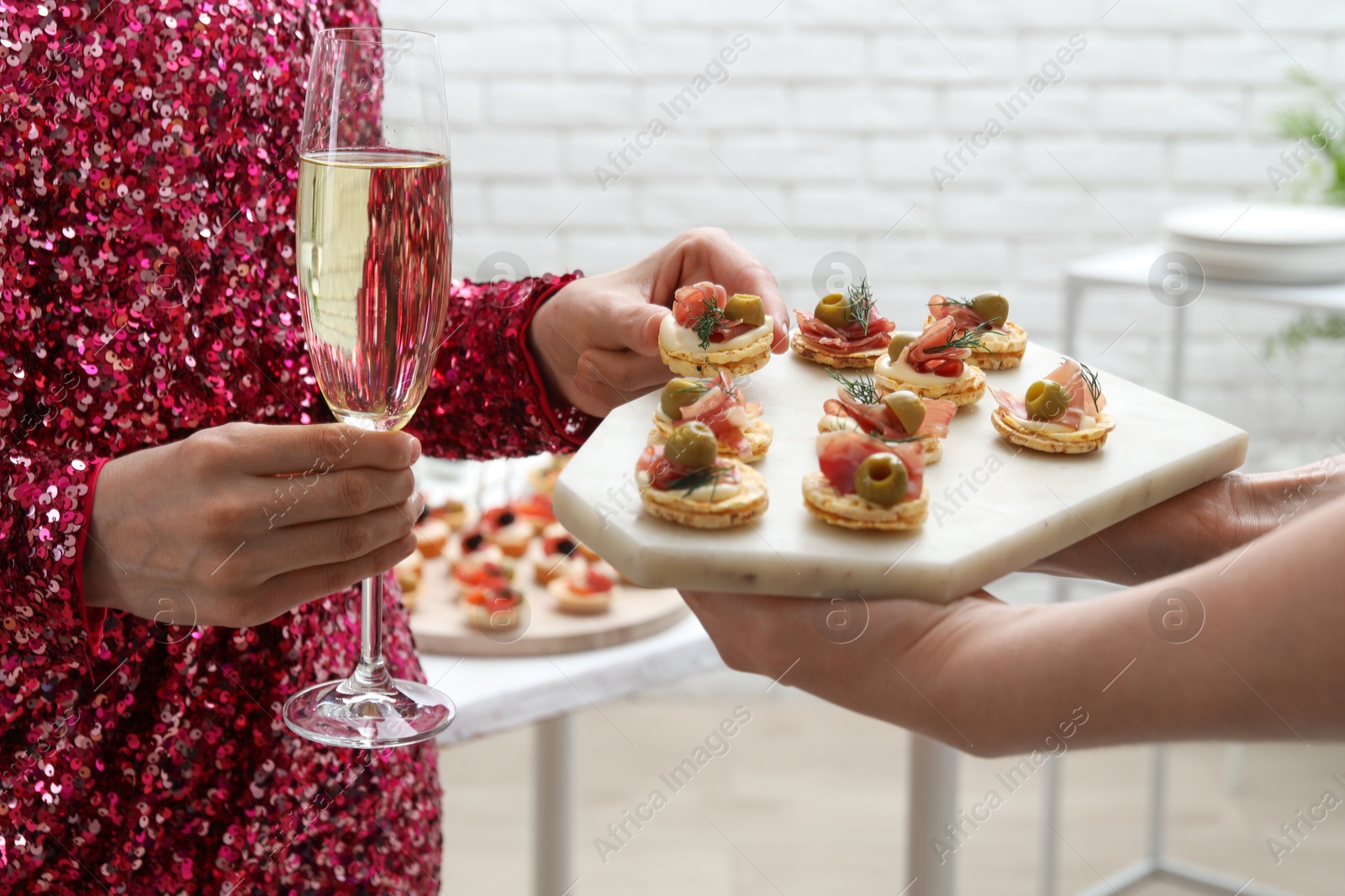 Photo of Woman taking tasty canape from waiter with board indoors, closeup