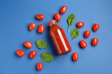 Photo of Tasty ketchup in bottle, tomatoes and basil on blue background, flat lay