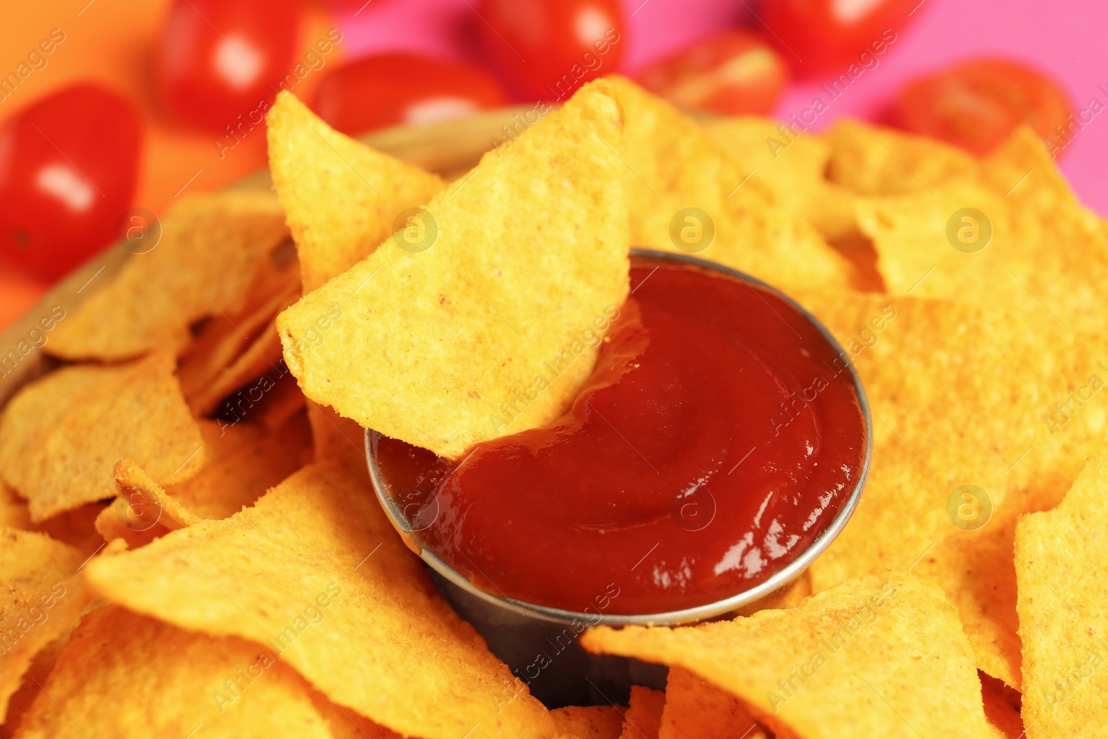 Photo of Tasty ketchup and nachos on color background, closeup