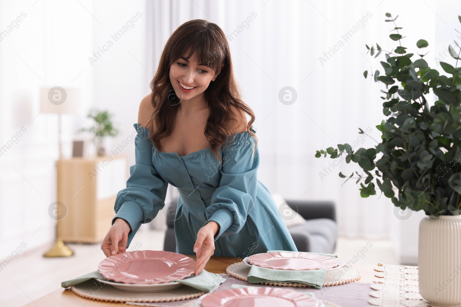 Photo of Woman setting table for dinner at home