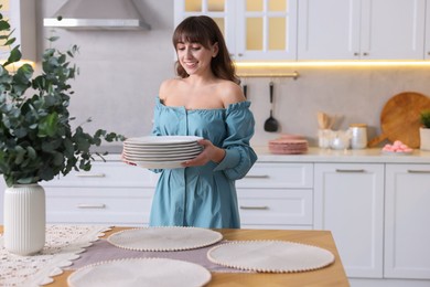 Woman setting table for dinner at home