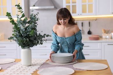 Photo of Woman setting table for dinner at home