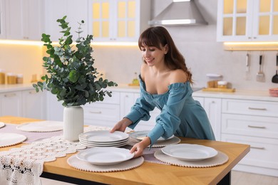 Woman setting table for dinner at home