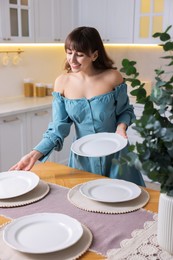 Woman setting table for dinner at home