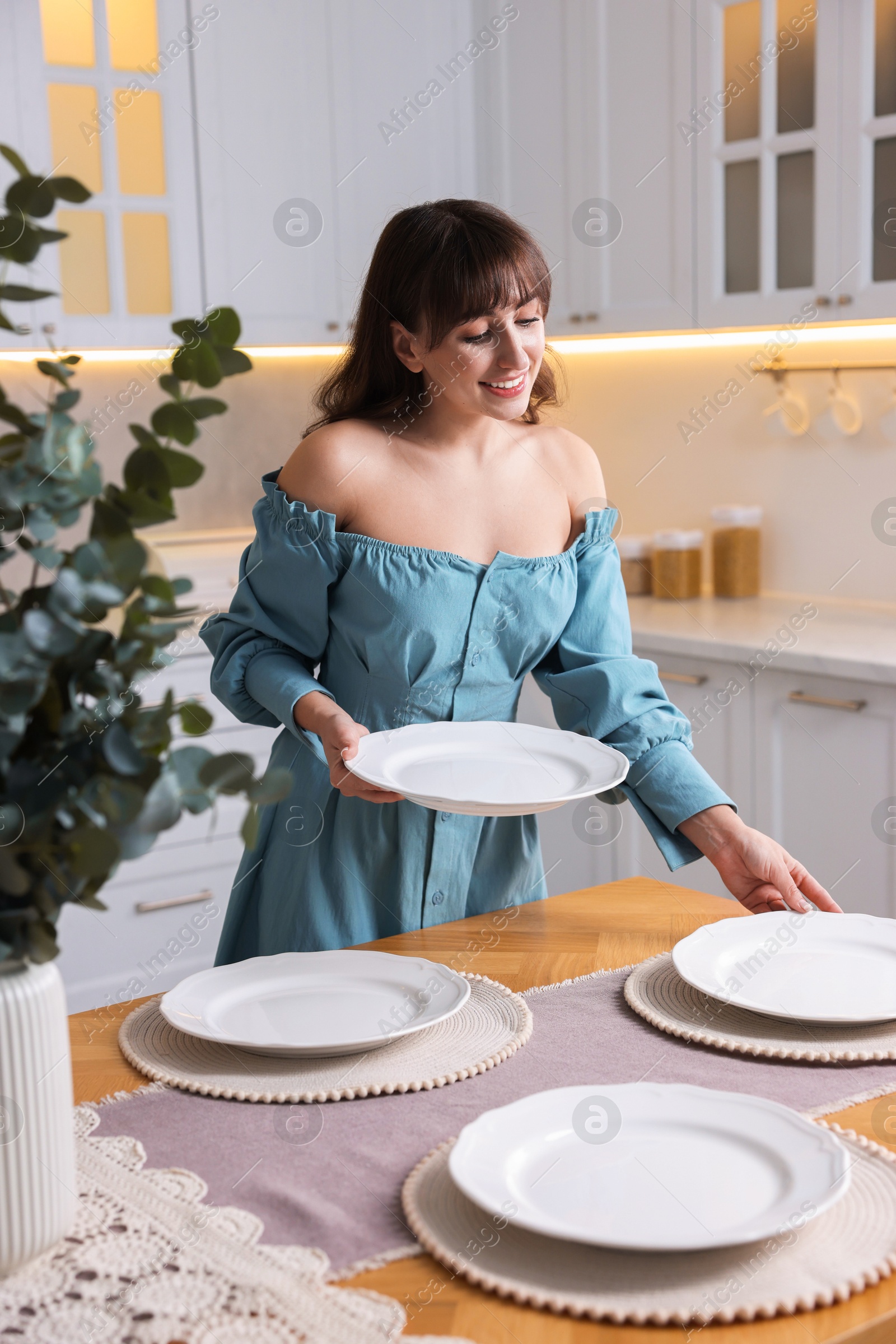 Photo of Woman setting table for dinner at home