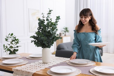 Photo of Woman setting table for dinner at home