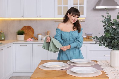 Woman setting table for dinner at home