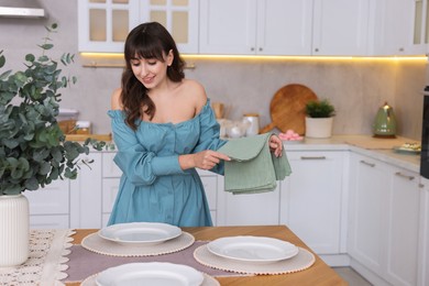 Woman setting table for dinner at home