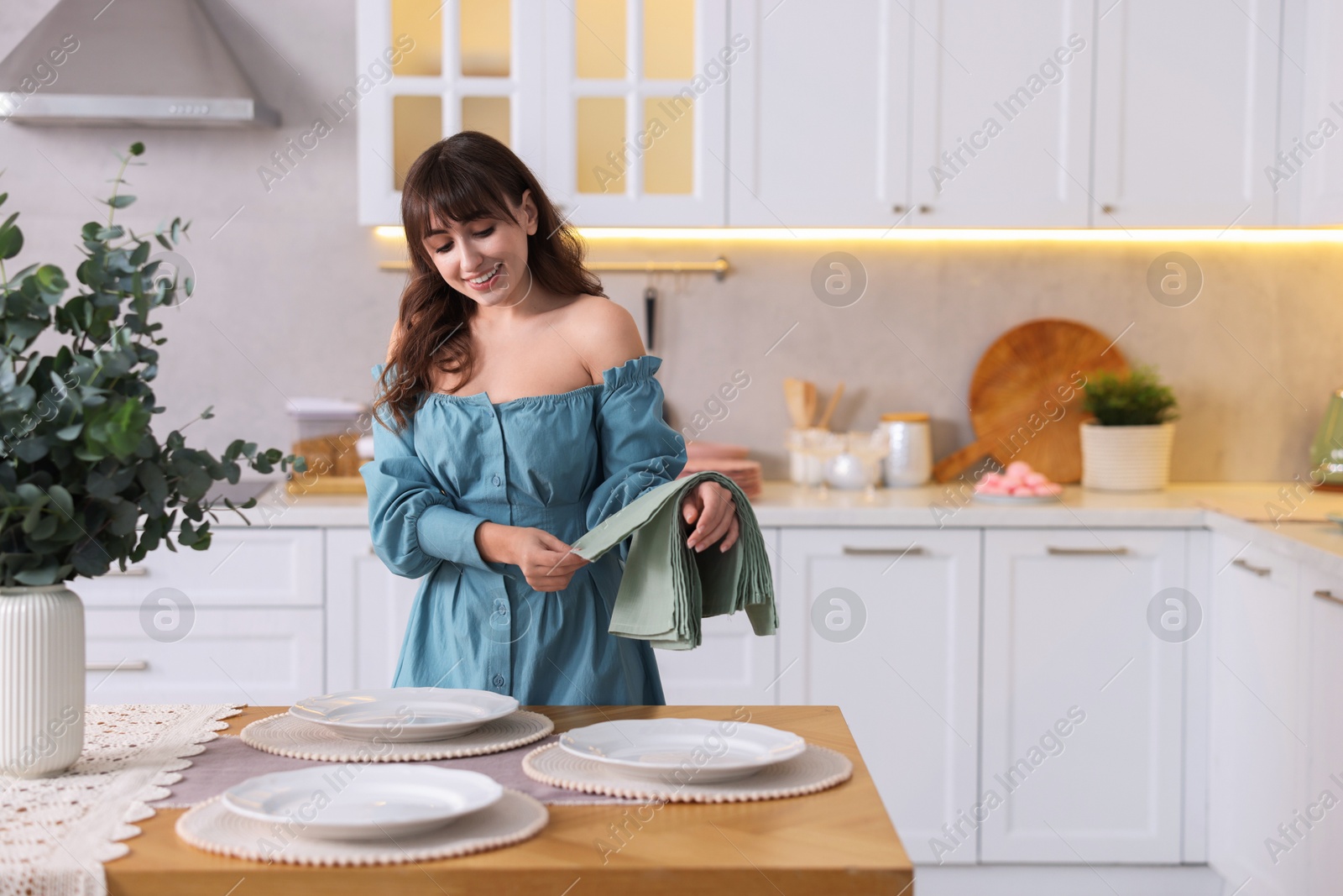 Photo of Woman setting table for dinner at home, space for text