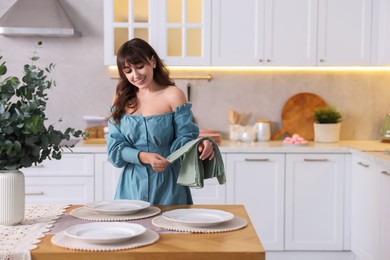 Woman setting table for dinner at home, space for text