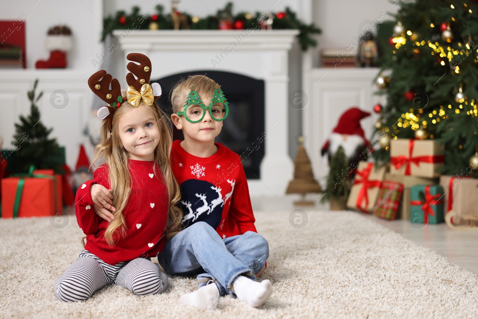 Photo of Cute little children in Christmas sweaters at home