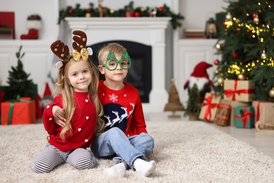 Photo of Cute little children in Christmas sweaters at home