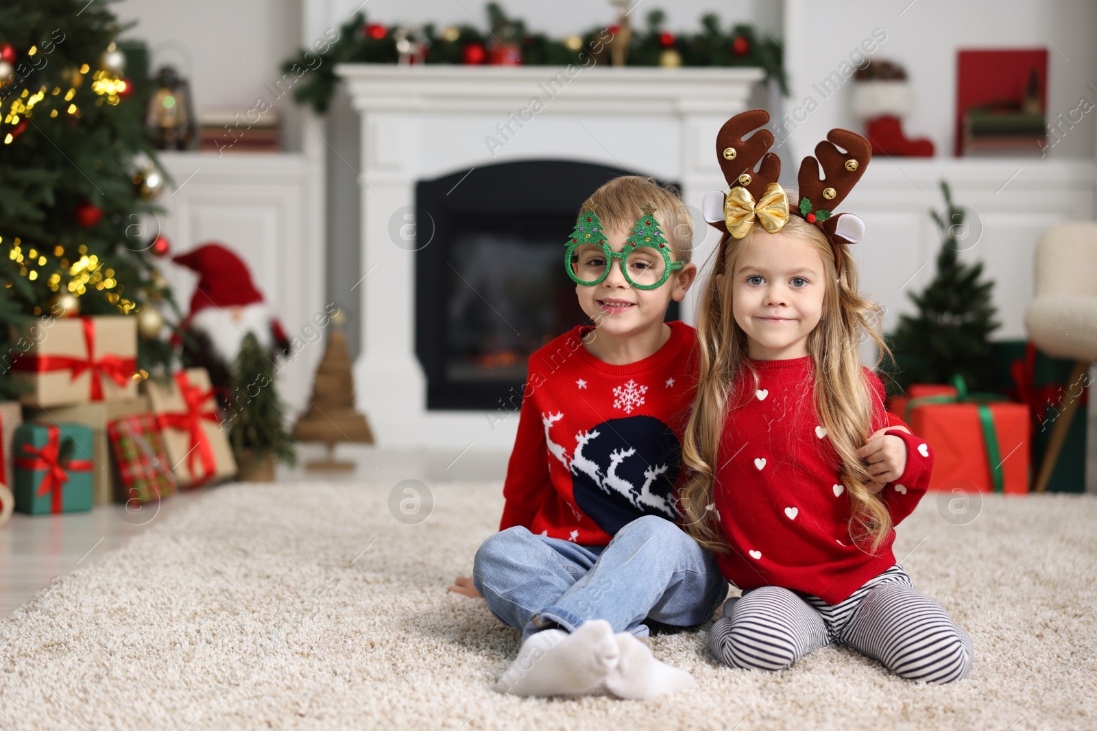 Photo of Cute little children in Christmas sweaters at home